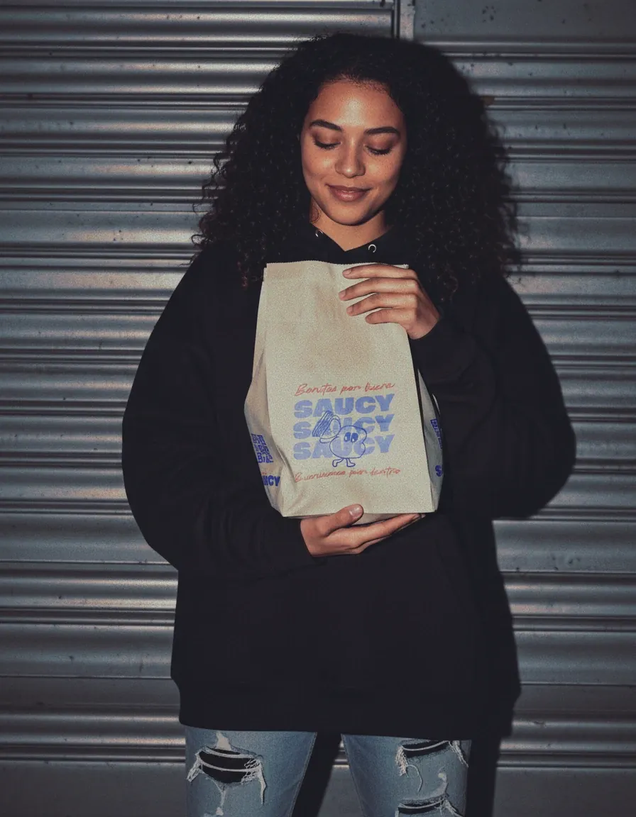 Persona con buzo negro sosteniendo la bolsa de papel de Saucy